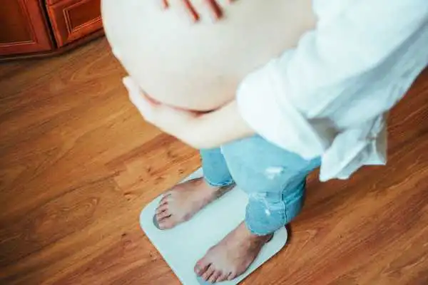 Image of woman weighing herself and experiencing weight gain through pregnancy Tetbury